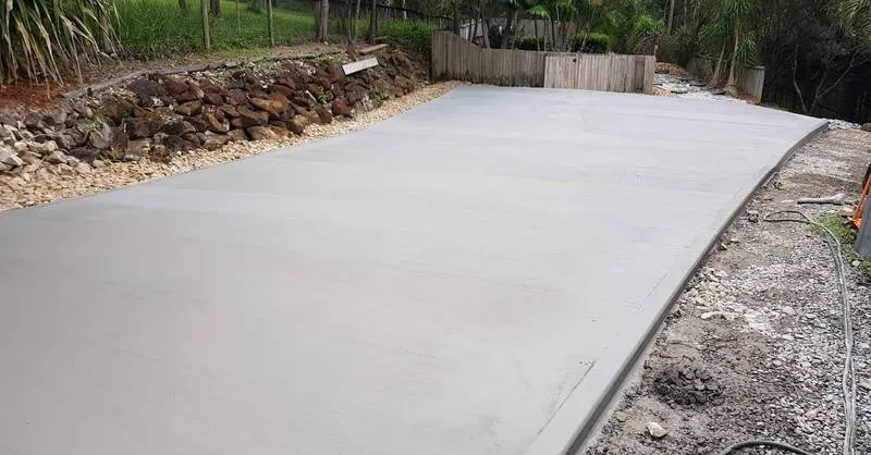 Smooth concrete slab poured by Riverstone beside a rock garden