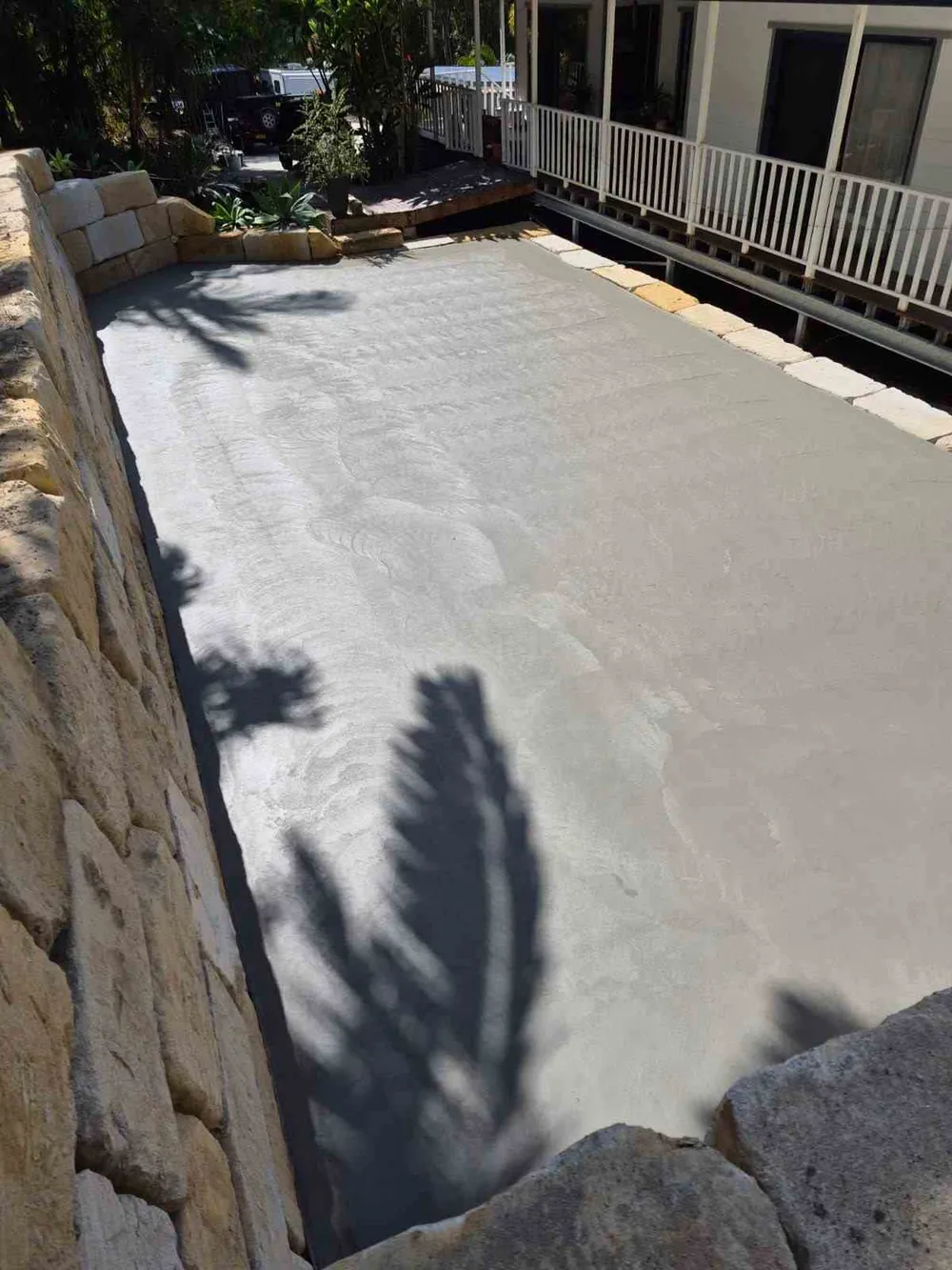 Freshly poured concrete slab beside sandstone block retaining walls